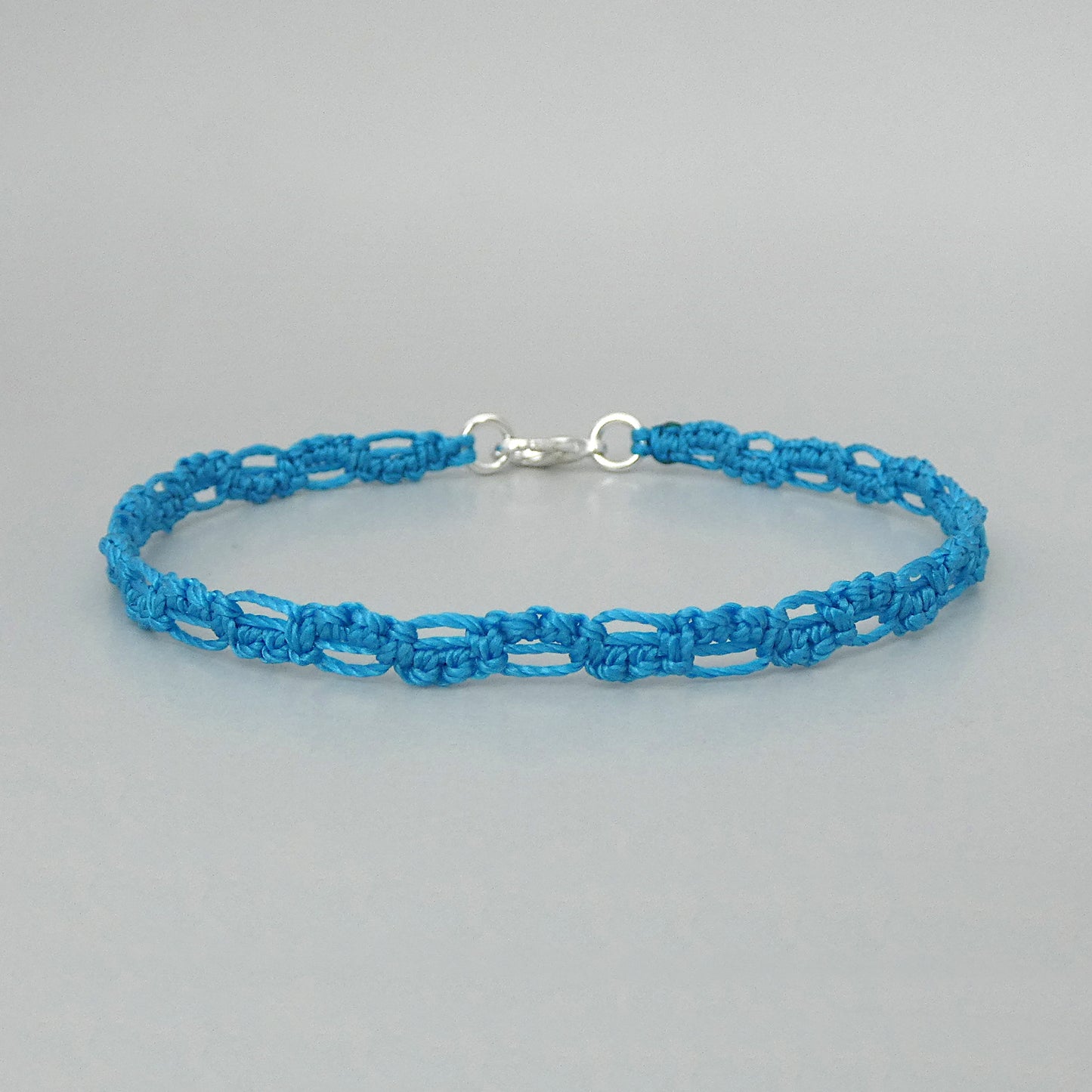 Bermuda blue macramé bracelet tied with an intricate lace effect with silver plated clasp and optional 1” extender chain.