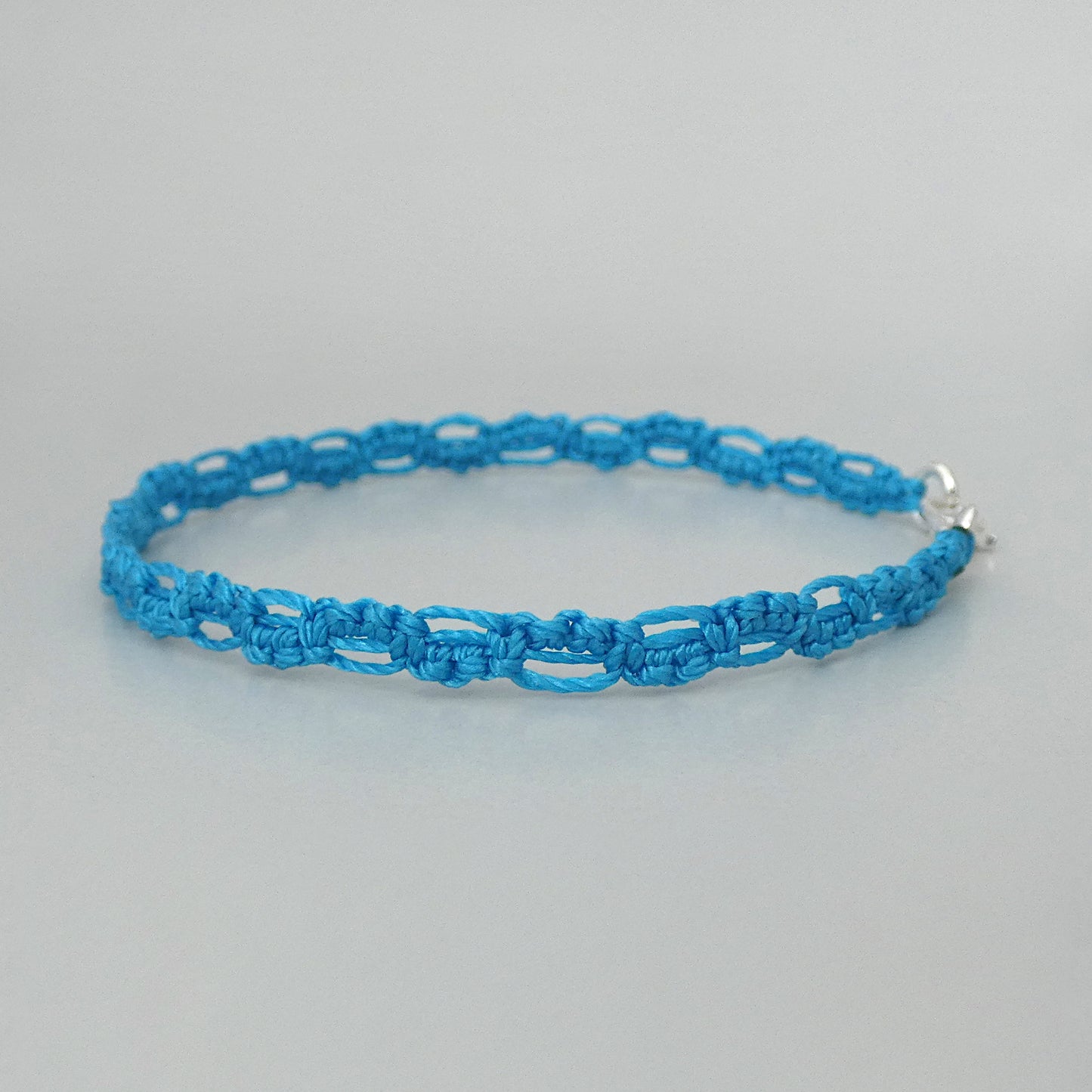 Bermuda blue macramé bracelet tied with an intricate lace effect with silver plated clasp and optional 1” extender chain.