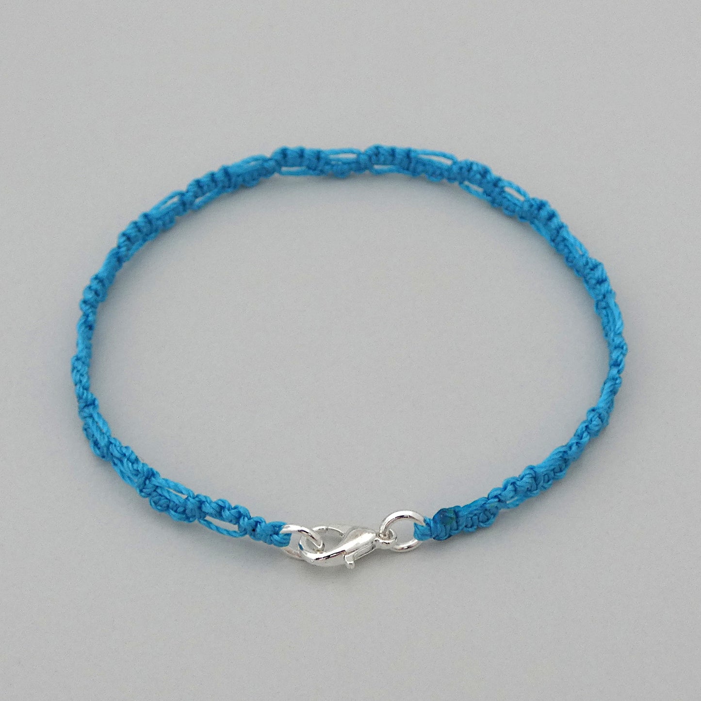 Bermuda blue macramé bracelet tied with an intricate lace effect with silver plated clasp and optional 1” extender chain.
