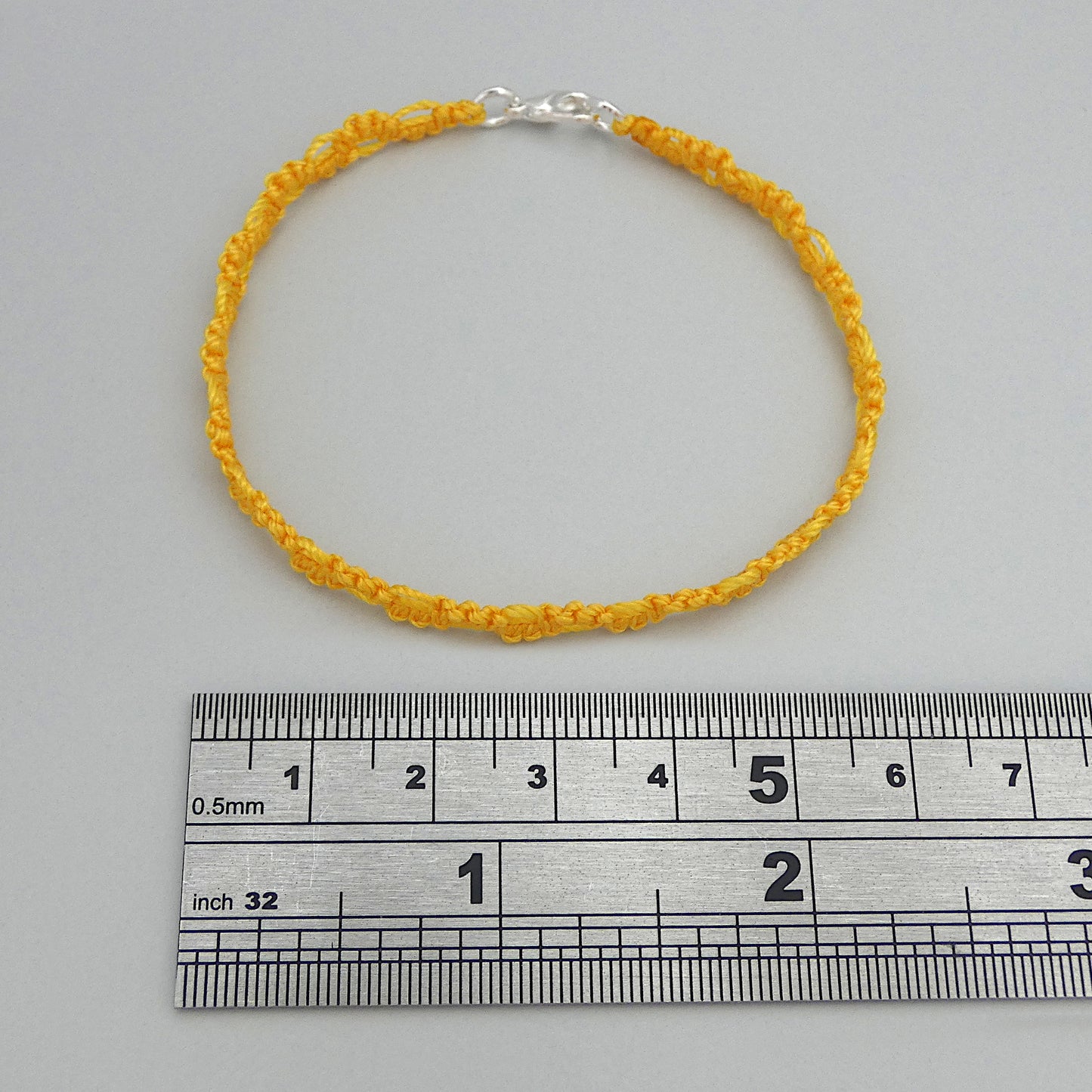 Golden yellow macramé bracelet tied with an intricate lace effect with silver plated clasp and optional 1” extender chain.
