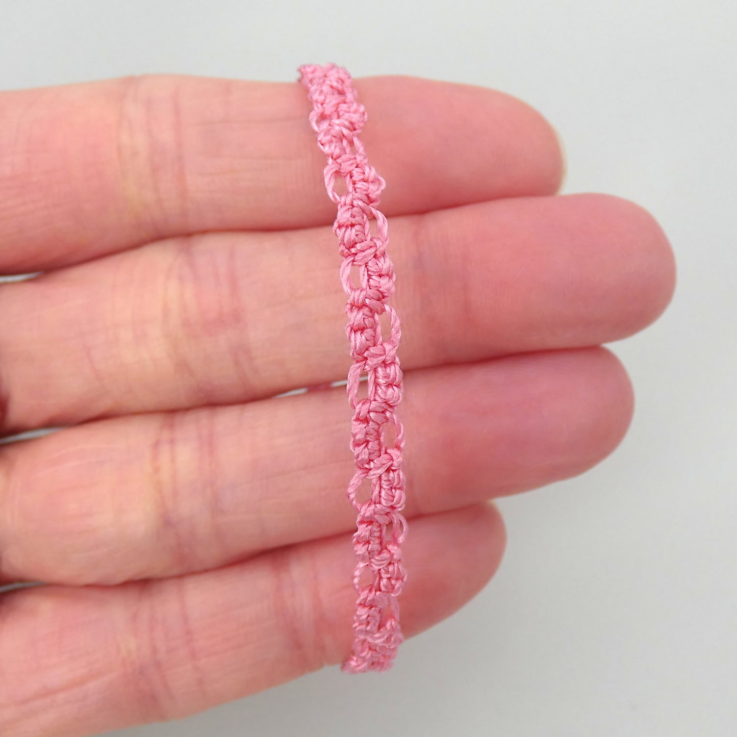 Pink macramé bracelet tied with an intricate lace effect with silver plated clasp and optional 1” extender chain.