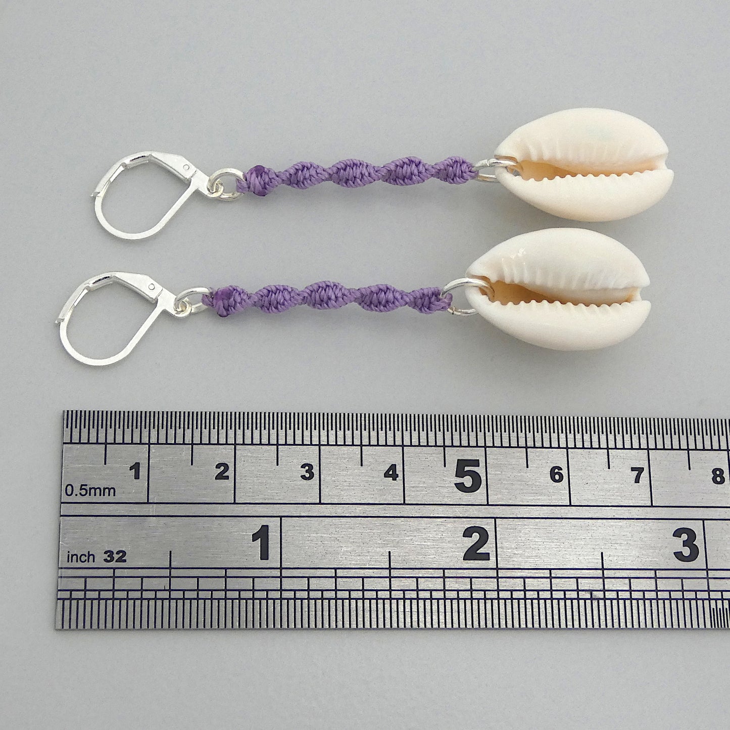Silver plated leverback earrings with cowrie shells and orchid purple macramé twist detail.