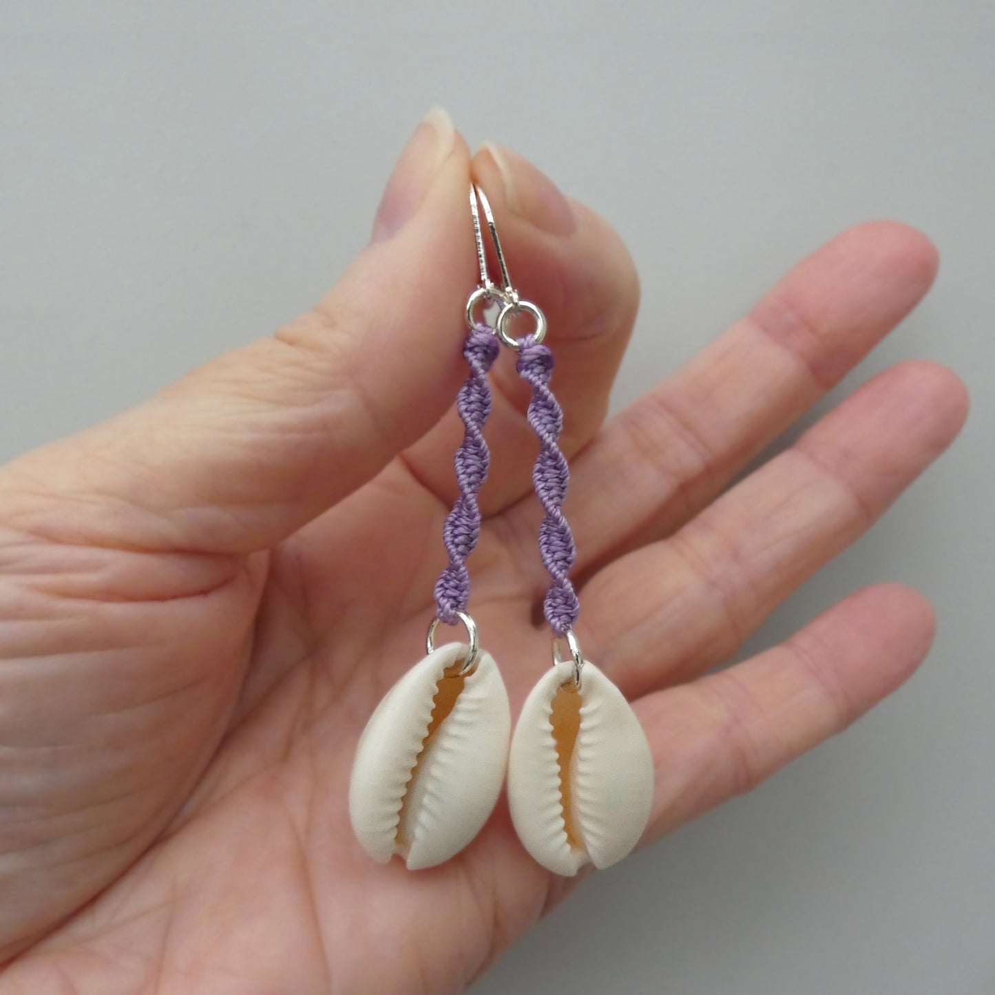 Silver plated leverback earrings with cowrie shells and orchid purple macramé twist detail.