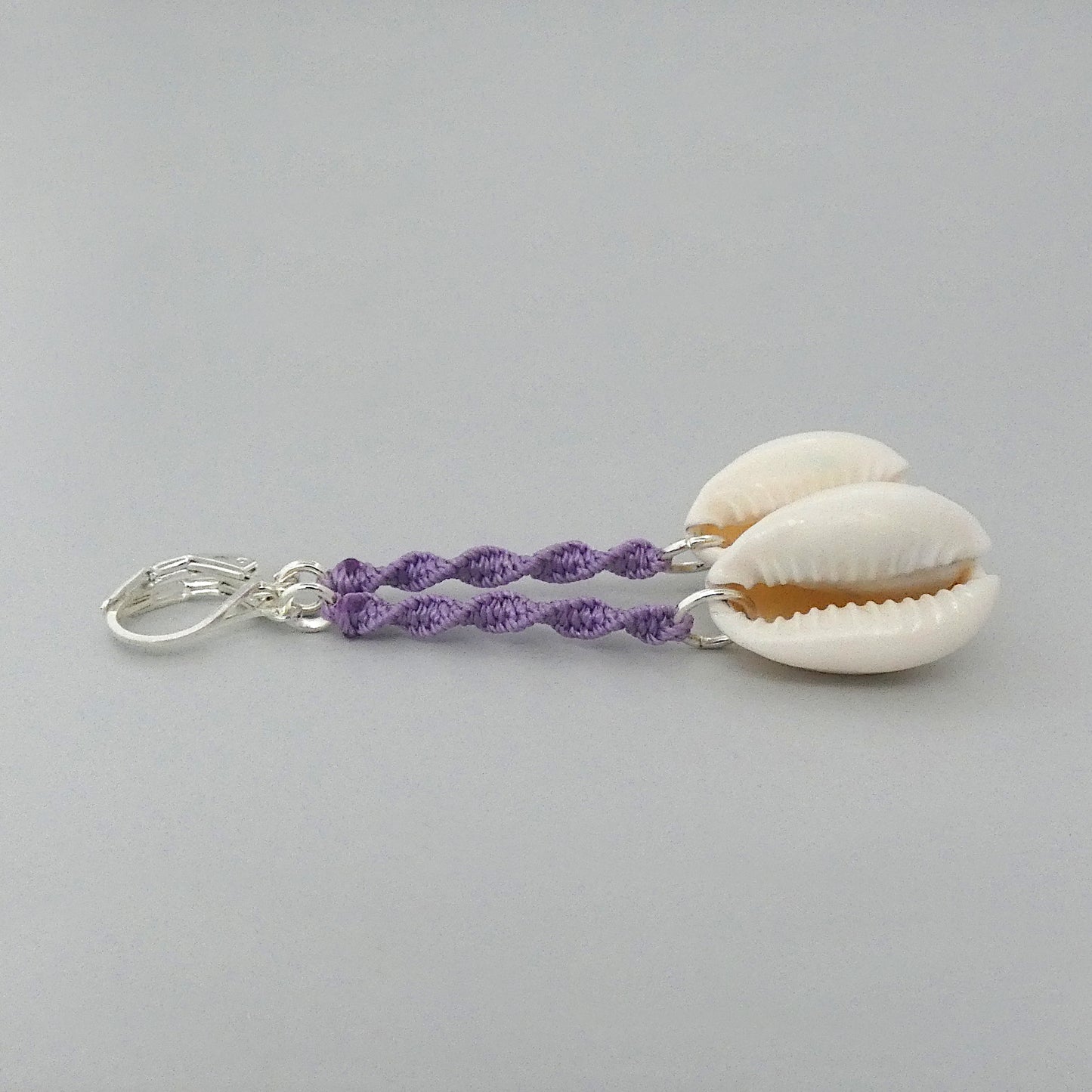 Silver plated leverback earrings with cowrie shells and orchid purple macramé twist detail.