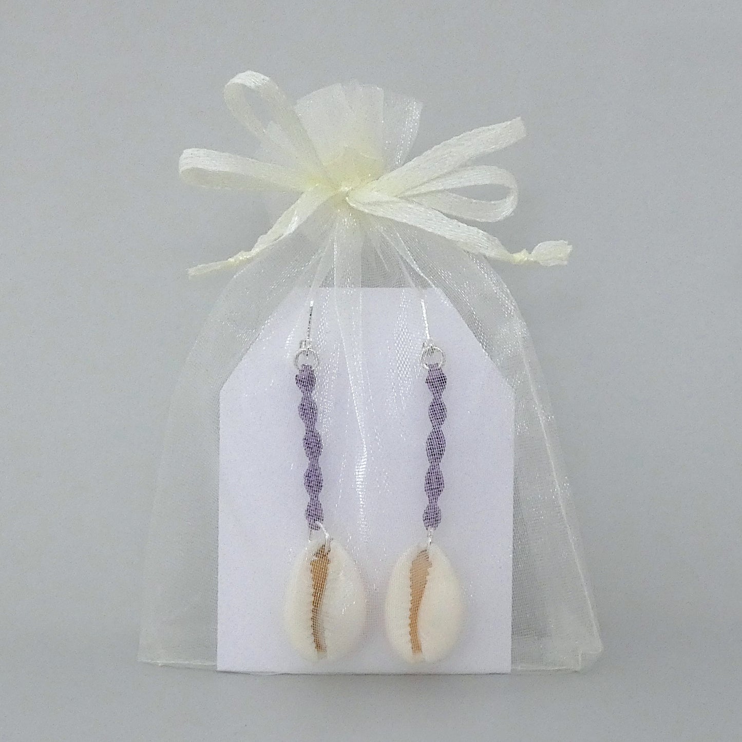 Silver plated leverback earrings with cowrie shells and orchid purple macramé twist detail.