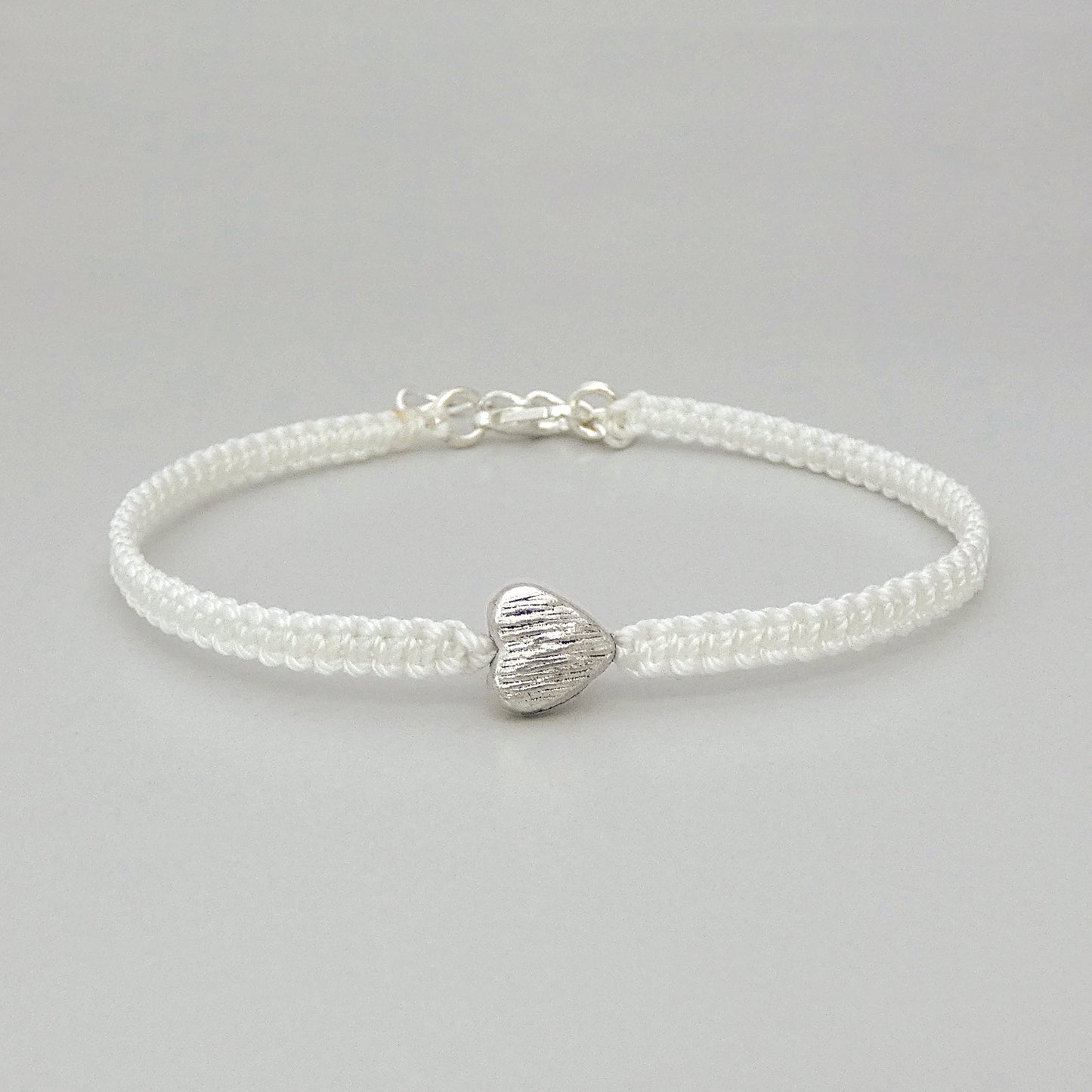 7" White adjustable dainty macramé bracelet with silver plated heart, clasp and extender chain.