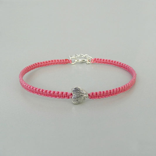 Pink seven inch macramé bracelet with silver plated textured heart charm, lobster clasp and one inch extender chain.